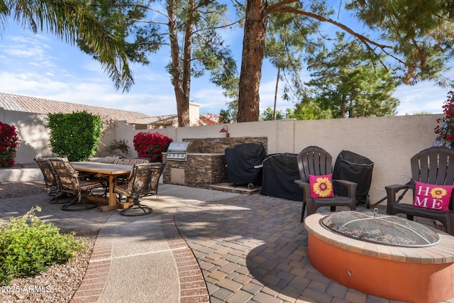 view of patio with exterior kitchen, a grill, and a fire pit