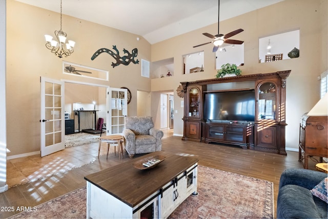 living room with hardwood / wood-style flooring, ceiling fan with notable chandelier, high vaulted ceiling, and french doors