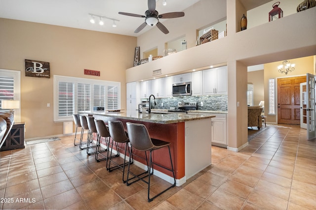 kitchen featuring sink, stone counters, a kitchen island with sink, stainless steel appliances, and white cabinets