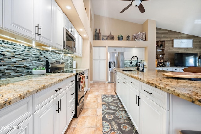 kitchen with appliances with stainless steel finishes, sink, white cabinets, and light stone counters