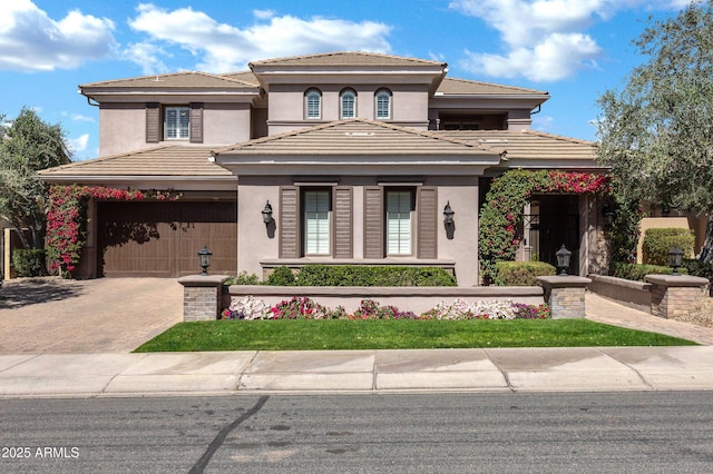 prairie-style home featuring a tiled roof, decorative driveway, an attached garage, and stucco siding