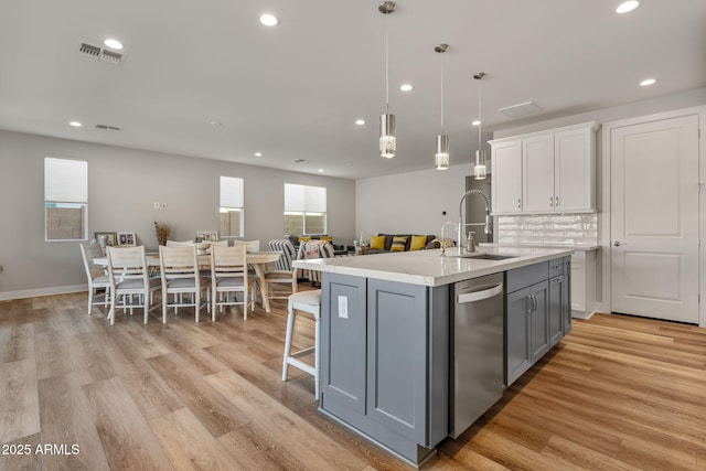 kitchen featuring gray cabinets, an island with sink, white cabinets, hanging light fixtures, and stainless steel dishwasher