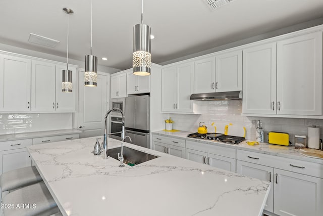 kitchen with sink, a kitchen island with sink, a kitchen breakfast bar, white cabinets, and decorative light fixtures