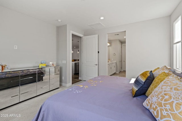 bedroom featuring ensuite bathroom and light colored carpet