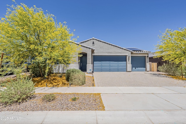 ranch-style home featuring driveway, an attached garage, a tiled roof, stucco siding, and roof mounted solar panels