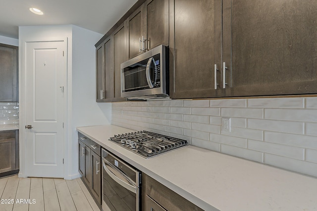 kitchen featuring stainless steel appliances, dark brown cabinetry, backsplash, light countertops, and recessed lighting