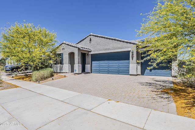 view of front of property with decorative driveway, an attached garage, stucco siding, and a tiled roof