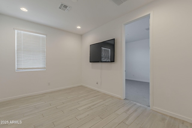 empty room featuring light wood-style floors, baseboards, and recessed lighting