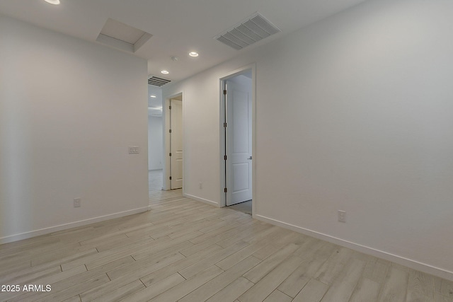 unfurnished room with light wood finished floors, baseboards, attic access, and recessed lighting