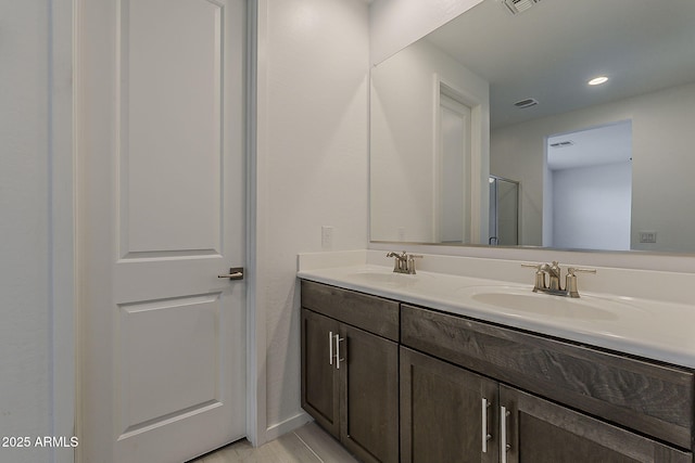 full bath featuring double vanity, a shower with door, and recessed lighting