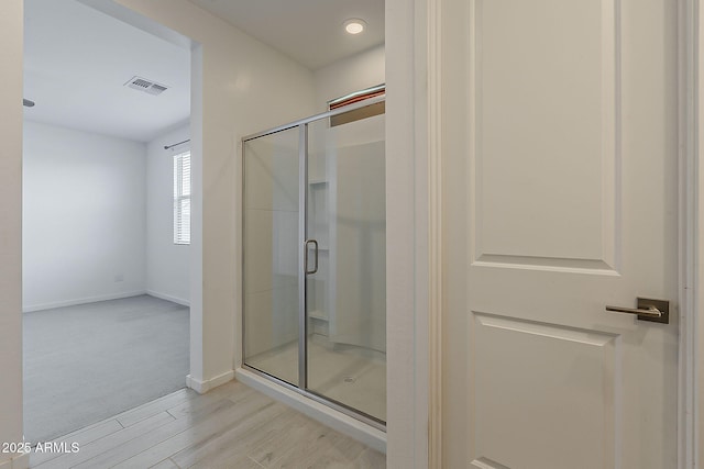 bathroom featuring a stall shower, wood finished floors, and baseboards