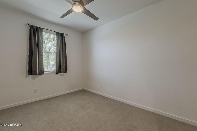spare room featuring ceiling fan, light colored carpet, and baseboards