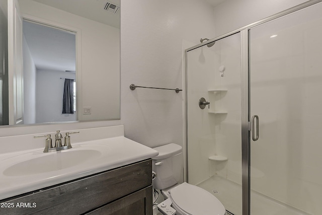 bathroom featuring a shower stall, toilet, and vanity