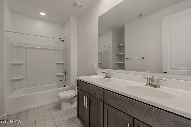 bathroom with toilet, double vanity, wood finished floors, and washtub / shower combination