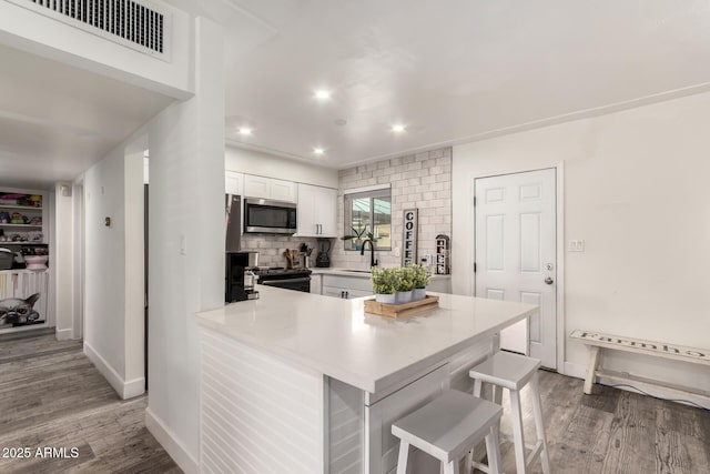 kitchen featuring sink, white cabinetry, a kitchen breakfast bar, tasteful backsplash, and kitchen peninsula