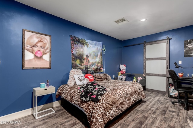 bedroom featuring wood-type flooring and a barn door