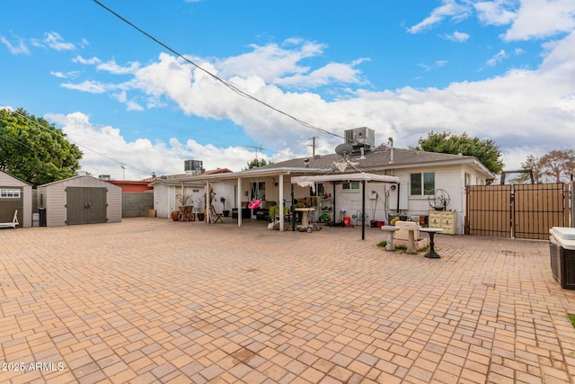 back of property with a storage unit, central AC unit, and a patio area