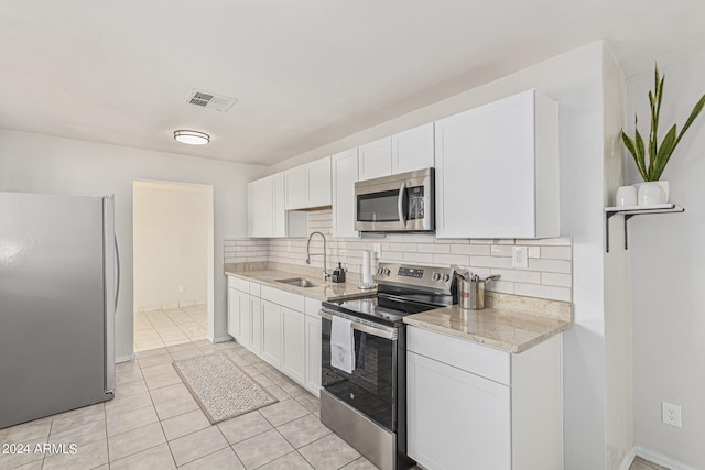 kitchen featuring white cabinets, tasteful backsplash, appliances with stainless steel finishes, light tile patterned flooring, and sink