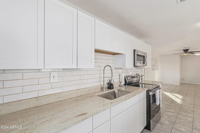 kitchen with decorative backsplash, stainless steel appliances, sink, light stone countertops, and white cabinetry