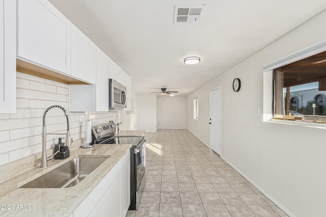 kitchen with stainless steel appliances, backsplash, sink, light stone countertops, and white cabinets