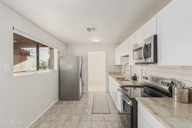 kitchen featuring tasteful backsplash, sink, stainless steel appliances, white cabinets, and light stone counters