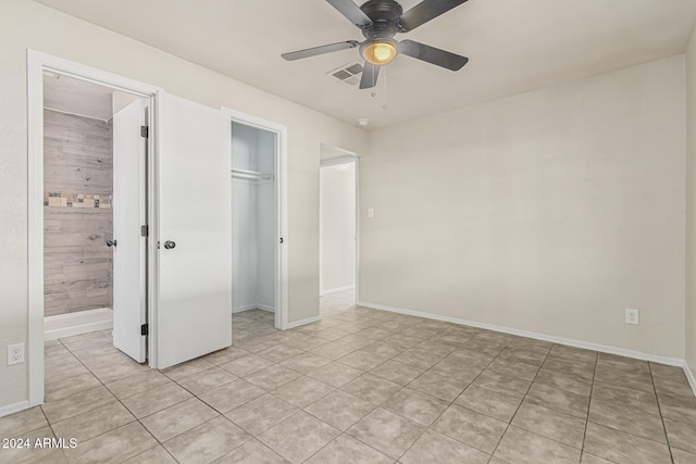 unfurnished bedroom with connected bathroom, light tile patterned floors, a closet, and ceiling fan