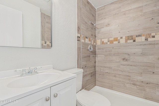 bathroom with a tile shower, toilet, a textured ceiling, and vanity