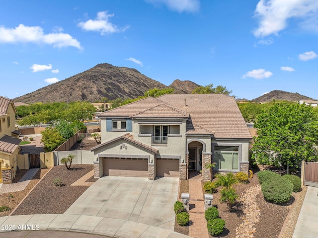 view of front facade with driveway, stucco siding, fence, an attached garage, and a mountain view