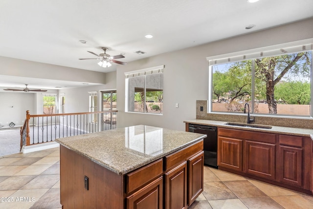 kitchen with a center island, a sink, ceiling fan, black dishwasher, and light stone countertops