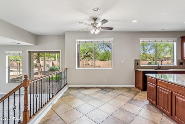 kitchen featuring a sink, a ceiling fan, light stone countertops, baseboards, and recessed lighting