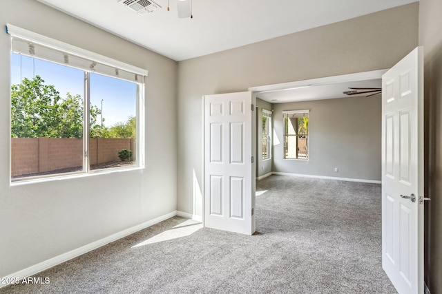 empty room with baseboards, carpet flooring, ceiling fan, and visible vents