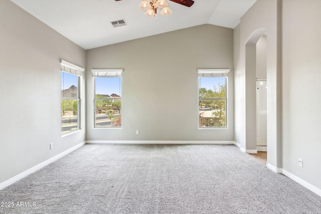 carpeted spare room with lofted ceiling, baseboards, arched walkways, visible vents, and a ceiling fan