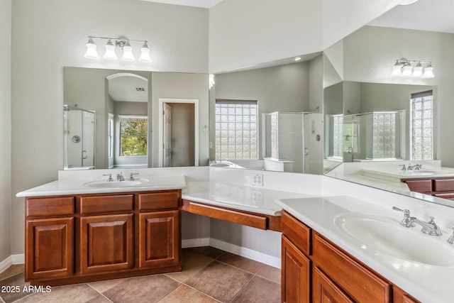 bathroom with a shower stall, a sink, and two vanities