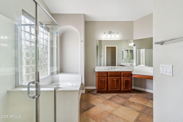 bathroom featuring vanity, baseboards, a shower stall, and a tub to relax in