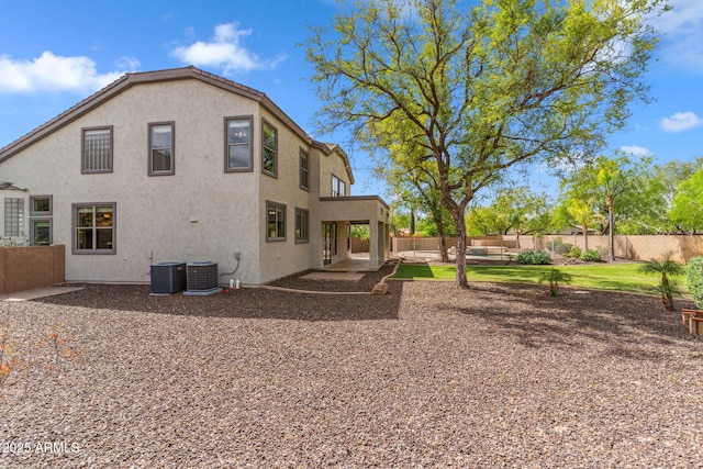 back of house with a fenced backyard, stucco siding, a patio, and central AC unit