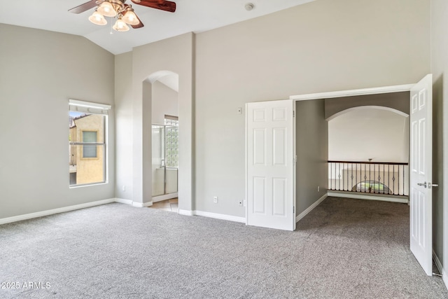 unfurnished bedroom featuring high vaulted ceiling, baseboards, arched walkways, ensuite bath, and carpet floors