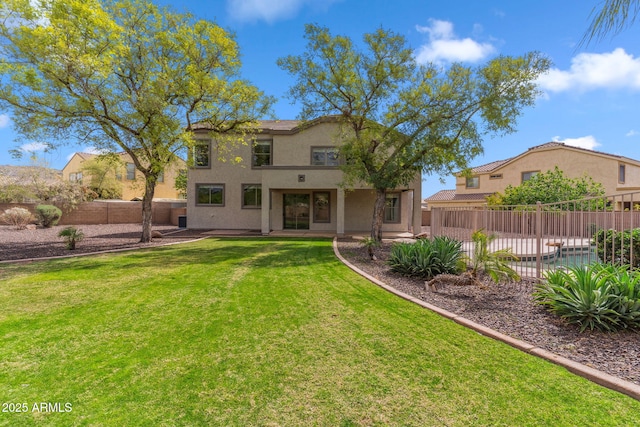 rear view of property with a yard, stucco siding, fence, and a patio area