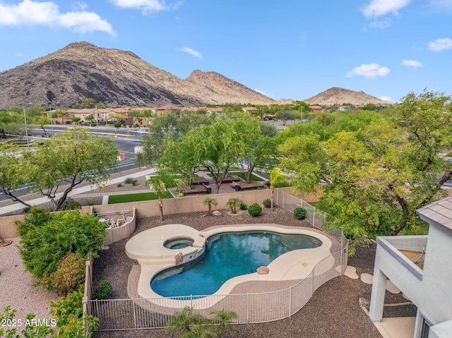 view of pool with a mountain view, a fenced backyard, and a pool with connected hot tub