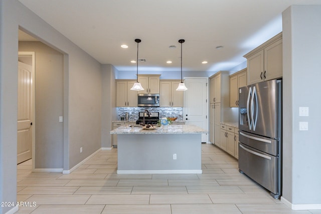 kitchen featuring an island with sink, backsplash, pendant lighting, appliances with stainless steel finishes, and light stone counters