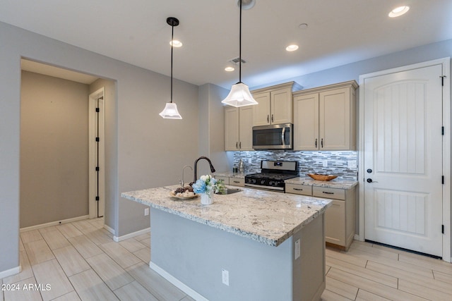 kitchen featuring a center island with sink, light stone countertops, decorative light fixtures, and stainless steel appliances