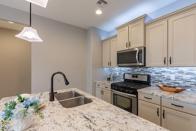 kitchen with cream cabinets, backsplash, sink, pendant lighting, and stainless steel appliances