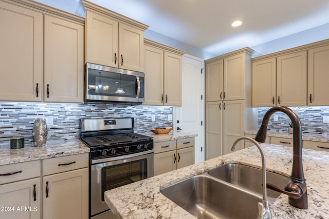 kitchen featuring light stone countertops, backsplash, appliances with stainless steel finishes, and cream cabinetry