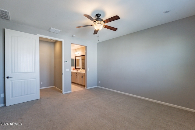 unfurnished bedroom with connected bathroom, sink, light colored carpet, and ceiling fan