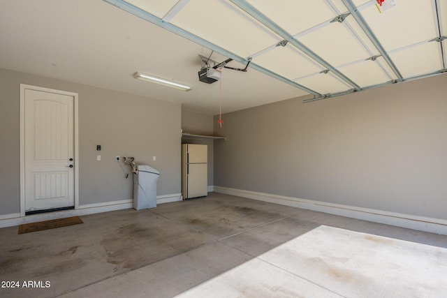 garage with a garage door opener and white fridge