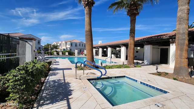 view of swimming pool featuring a hot tub and a patio area