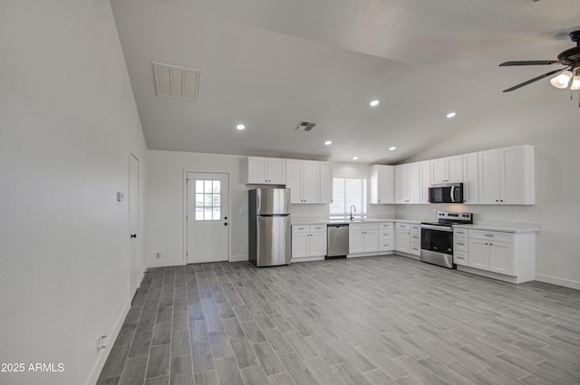 kitchen featuring lofted ceiling, visible vents, baseboards, appliances with stainless steel finishes, and ceiling fan