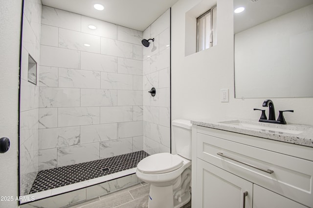 full bathroom featuring recessed lighting, a tile shower, toilet, and vanity