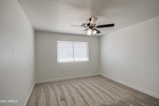carpeted spare room with baseboards, a ceiling fan, and a textured ceiling