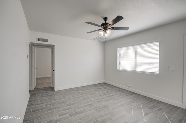 unfurnished room featuring baseboards, a ceiling fan, and visible vents