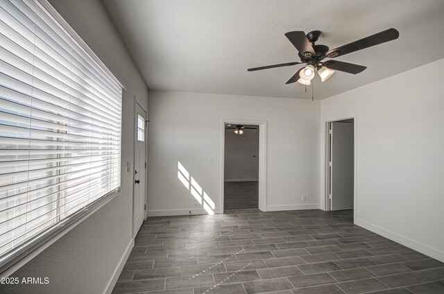 spare room with baseboards, ceiling fan, and dark wood finished floors